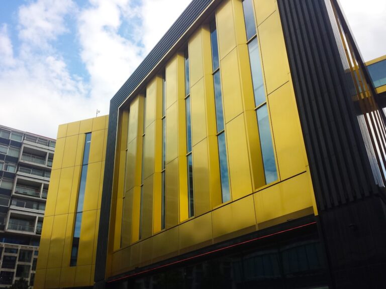 Um Edificio Amarelo Com Muitas Janelas E Um Fundo Do Ceu f0n7q6tcaxE