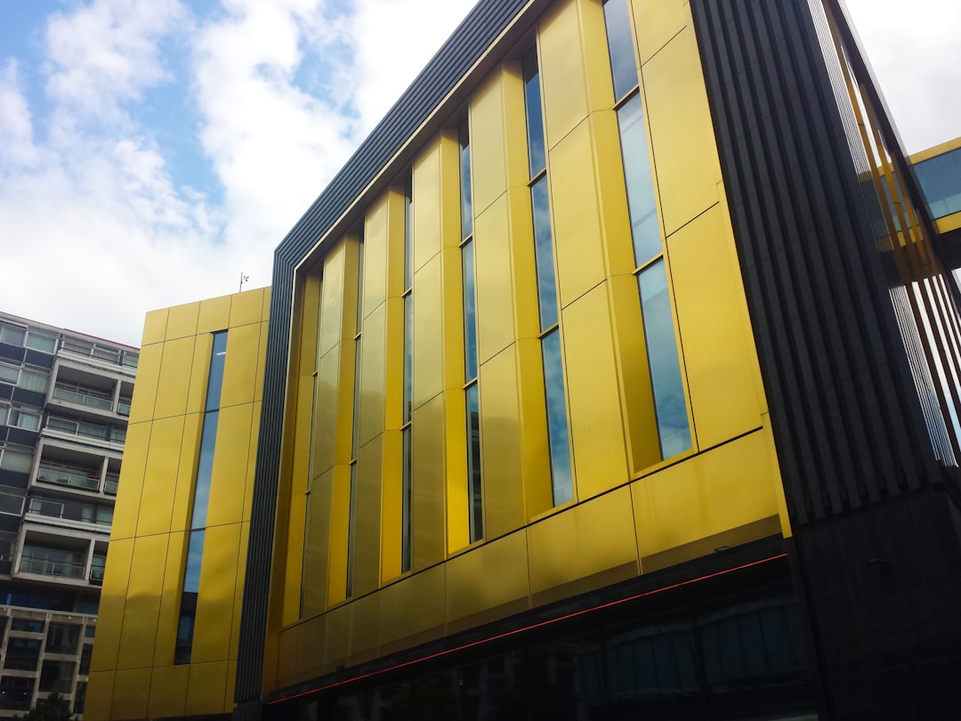 Um Edificio Amarelo Com Muitas Janelas E Um Fundo Do Ceu f0n7q6tcaxE