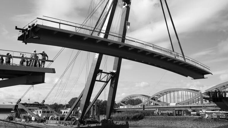 Trabalhadores Levantando Uma Grande Secao De Ponte Com Guindaste Fev7s7NQM3o