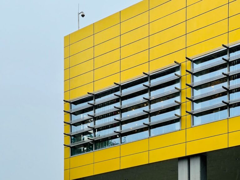 Um Edificio Amarelo Alto Com Janelas E Varandas bAxf7M__FVU