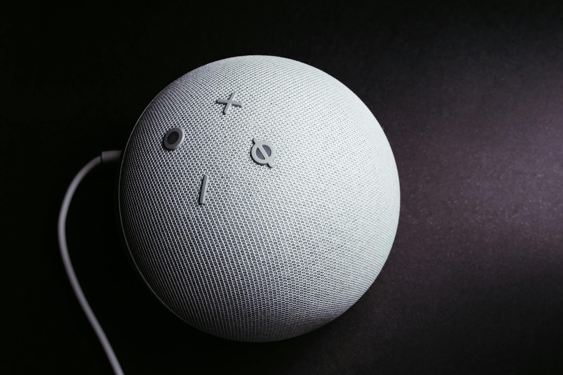 Close-up of a smart speaker on a black background, showcasing minimalistic elegance.