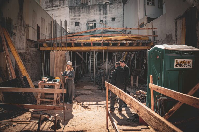 Construction site with workers and architect reviewing plans in bright daylight.