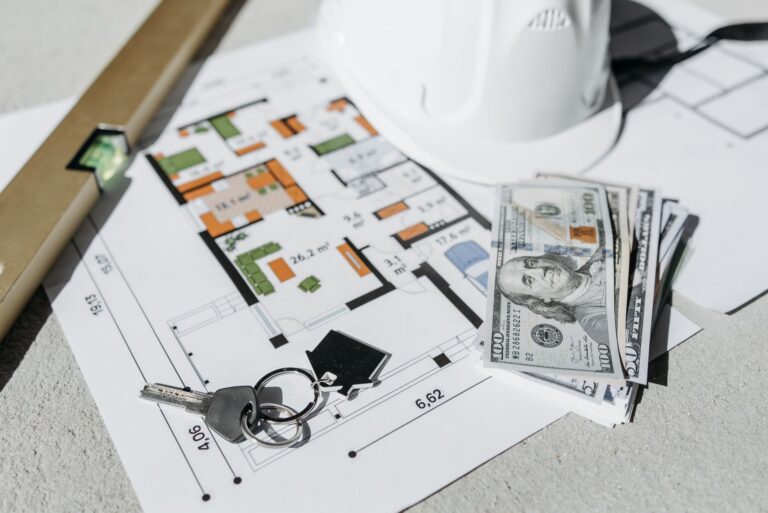 Floor plan with cash, keys, and hard hat symbolizing real estate investment and property planning.