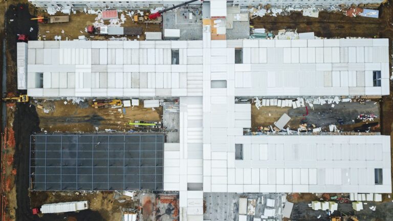 Drone shot capturing aerial view of a large construction site with unfinished buildings.