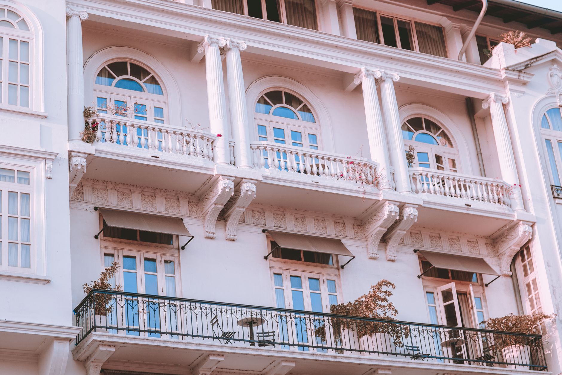 A sophisticated image of a white building featuring classic balconies and arched windows.