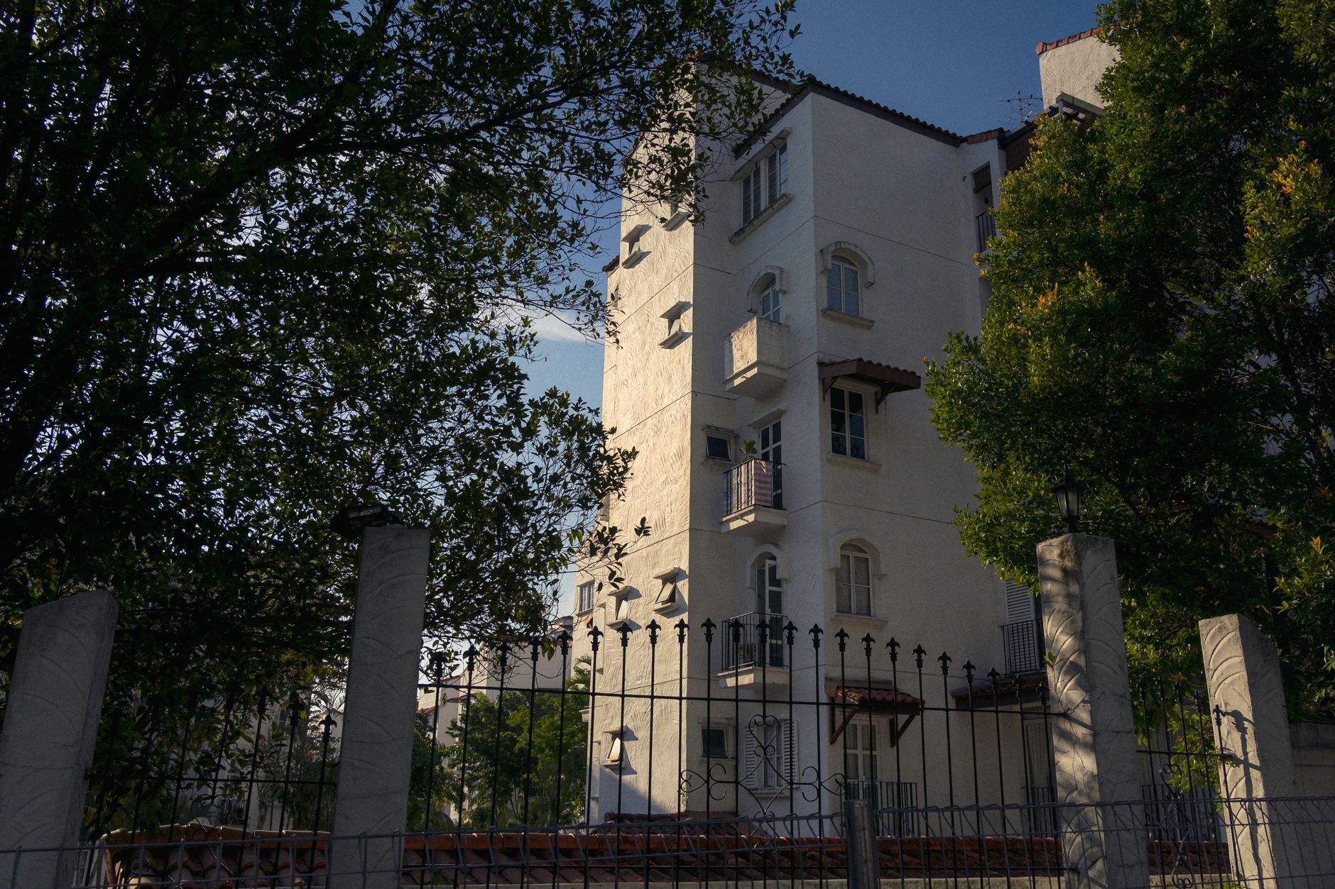Modern apartment building in sunlight, Kuala Lumpur, surrounded by trees, offering urban living ambiance.