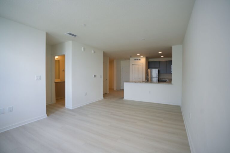 Spacious and empty modern open-plan apartment showing kitchen and living area.