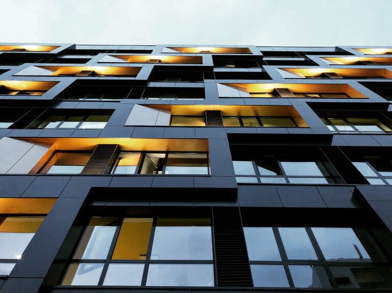 A modern apartment building facade in Moscow with geometric window designs and warm lights.