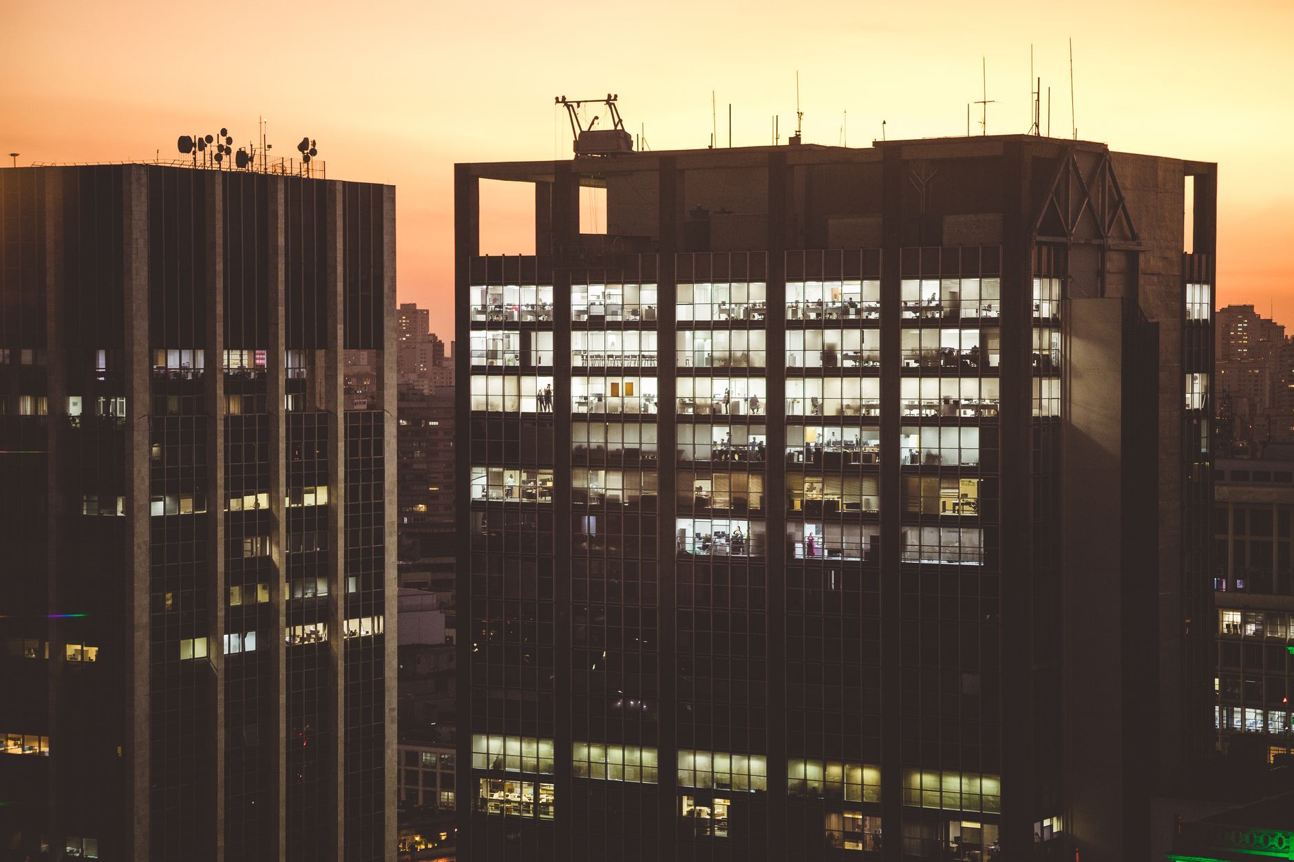 City office buildings illuminated against a sunset backdrop, showcasing urban life.