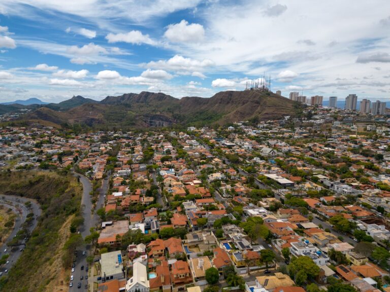 Aerial shot of Belo Horizonte, featuring homes and Serra do Curral mountains under a vibrant sky.