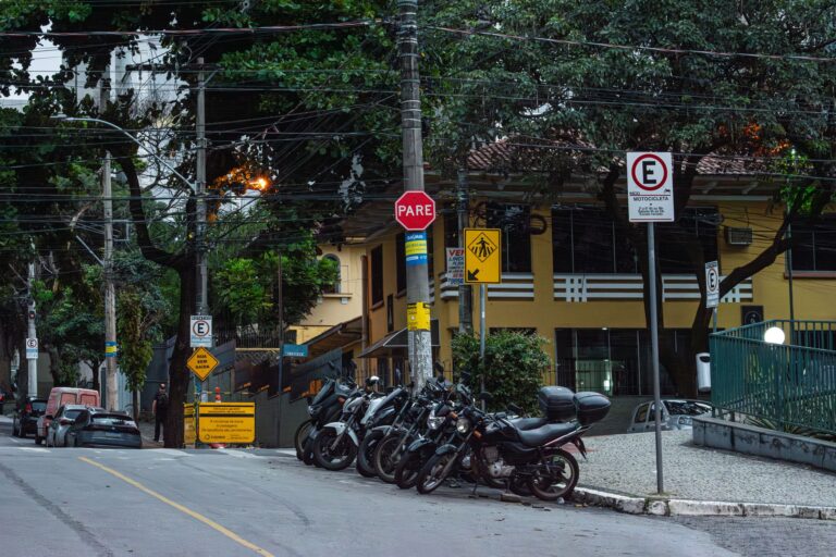 Motorcycles parked on a street in Belo Horizonte, Brazil, with various street signs.