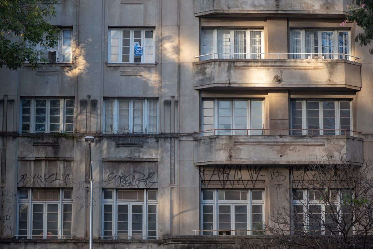 A detailed look at a weathered building facade in Belo Horizonte, Brazil, marked by graffiti and aged windows.