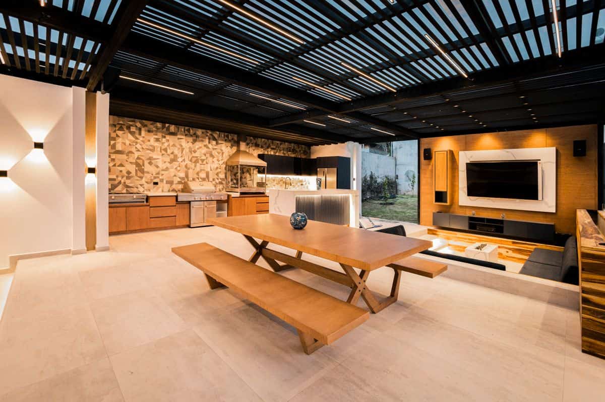 Spacious outdoor kitchen and living space featuring sleek design, wood accents, and a mounted TV.